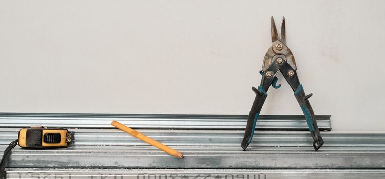 gipszkarton profil szereléshez, mérőszalaggal, ceruzával és lemezvágó fogóval a munkapadon